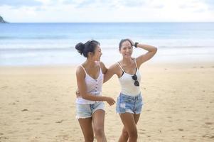 Two attractive women friends enjoying and relaxing on the beach,  Summer, vacation, holidays, Lifestyles concept. photo