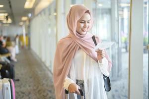 joven viajera musulmana que lleva maletas en el aeropuerto internacional, viajes, vacaciones y concepto de viaje. foto