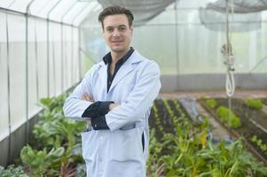 A scientist man is analyzing organic vegetables plants in greenhouse , concept of agricultural technology photo