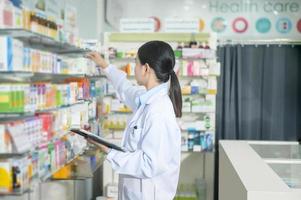 Portrait of female pharmacist using tablet in a modern pharmacy drugstore. photo