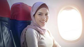 Young muslim woman wearing hijab using smartphone onboard, travel and holidays concept photo