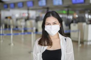 una mujer viajera lleva una máscara protectora en el aeropuerto internacional, viaja bajo la pandemia de covid-19, viajes de seguridad, protocolo de distanciamiento social, nuevo concepto de viaje normal. foto