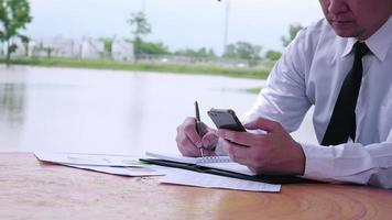 Businessman seriously work with document near water pond background video