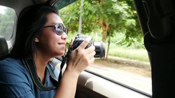 Tourist woman sitting in car happy looking outside to take photo a nature scene at local street travel video