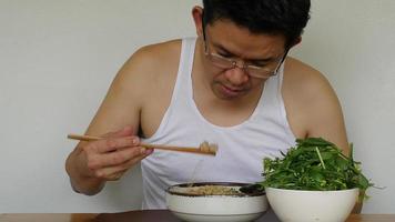 Aziatische man die zelfgemaakte instantnoedels eet met verse groene groente - lokale mensen met een snel voedselconcept voor thuis video