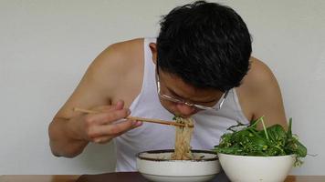 Aziatische man die zelfgemaakte instantnoedels eet met verse groene groente - lokale mensen met een snel voedselconcept voor thuis video