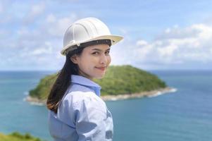 Female engineer working on the seaside wearing a protective helmet photo