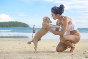 Young Beautiful woman in Bikini with her dog enjoying and relaxing on the beach,  Summer, vacation, holidays, Lifestyles concept. photo