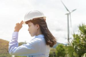 ingeniera que trabaja en la playa con un casco protector sobre el fondo de las turbinas eléctricas. foto