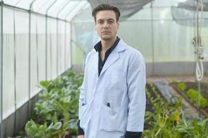 A scientist man is analyzing organic vegetables plants in greenhouse , concept of agricultural technology photo