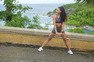 A Beautiful fit woman in sportswear exercising on seaside mountain peak, Health and Travel concept. photo