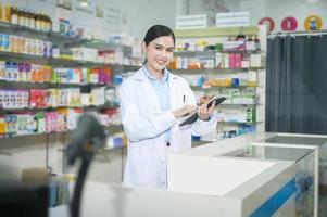 Portrait of female pharmacist using tablet in a modern pharmacy drugstore. photo