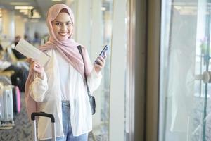 Young female muslim traveler carrying suitcases at the International airport, travel, holidays and journey concept. photo