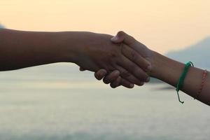 handshake represents friendship, friendly touch - love - warmth in the family and others on the background, the sky and the mountains in the evening. photo