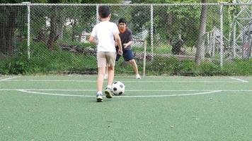 Dad and son happy play soccer or football in artificial grass green field - family happy activity concept video