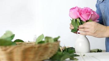 Mädchen, das fröhlich rosa Rosen in eine weiße Vase steckt video