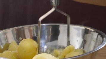 Lady smash boiled potato in a big bowl - people cooking potato concept