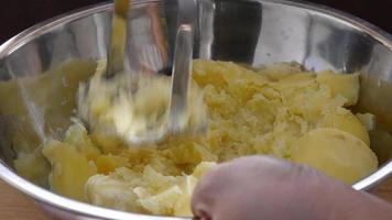 Lady smash boiled potato in a big bowl - people cooking potato concept