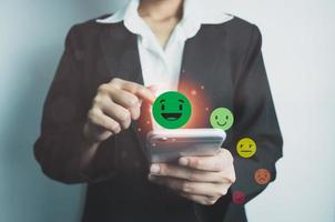 Customer satisfaction concept, client is satisfied with pressing smile face icon by smart phone, excellent service, impressed with care, highest rating and score, good feedback from users. photo