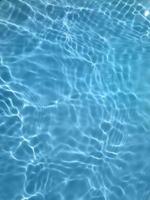 Defocus blurred blue water in swimming pool rippled water detail background. Water surface in the sea, ocean background. Water is an inorganic, transparent, tasteless, odorless, and nearly colorless. photo