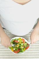 mujer embarazada comiendo ensalada de verduras, saludable para el nuevo concepto familiar foto