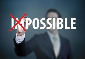 Businessman hand Changing the word impossible to possible with red marker on transparent board, new business concept, studio shot photo