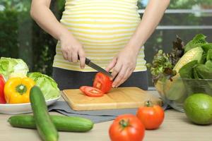 mujer embarazada cocinando con vegetales, saludable para un nuevo concepto familiar foto