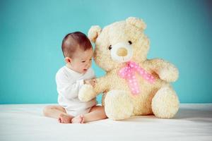 niña asiática jugando con su oso de peluche, niño sano con un nuevo concepto de familia foto