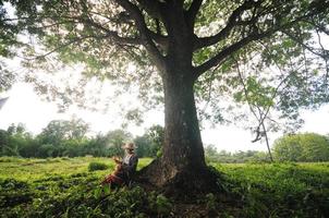 abuela asiática pescadora bajo un gran árbol