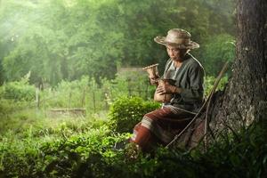 abuela asiática pescadora bajo un gran árbol foto