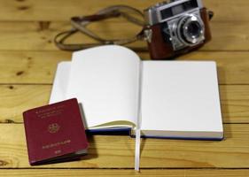 Empty travel journal, passport, and old-fashioned camera on a wooden table photo