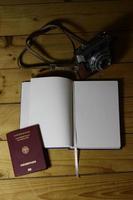 Empty travel journal, passport, and old-fashioned camera on a wooden table photo