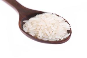 Raw and uncooked rice in wooden spoon over white background photo
