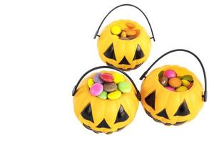 Halloween pumpkin face buckets with colorful candy inside isolated over white photo