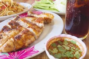 comida picante al estilo tailandés, pollo a la parrilla con ensalada de papaya picante y bebida fría foto
