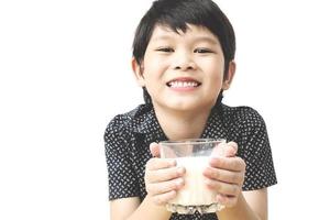 Asian boy is drinking a glass of milk over white background. Photo is focused at his hand.