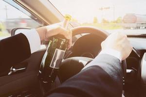 Man holding beer bottle while driving a car photo