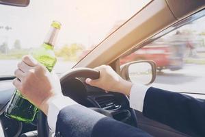 Man holding beer bottle while driving a car photo