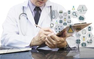 Male doctor is note down a document with medical icons overlay photo