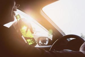 Man drinking beer while driving a car photo