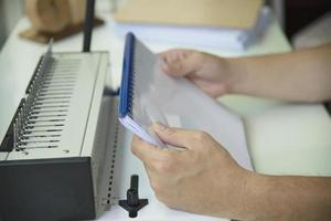 Man making report using comb binding machine - people working with stationary tools concept photo