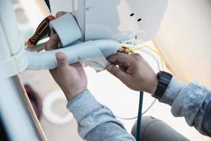 Man is installing wall compressor of air conditioner during hot season photo