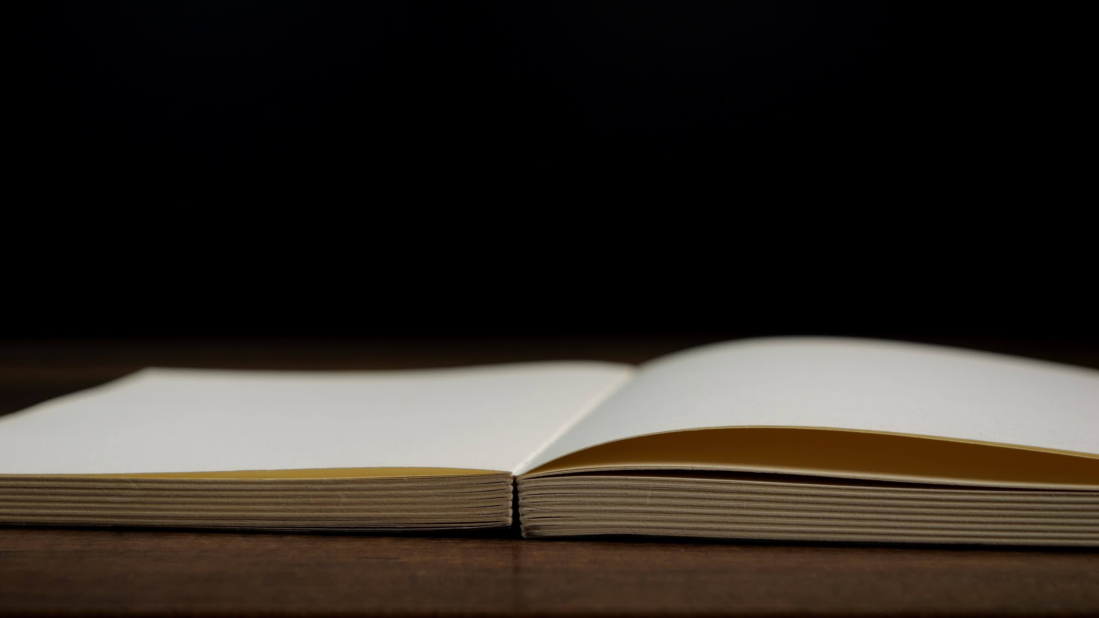 4K-Slow motion of open book with blank page fallowing on wooden table