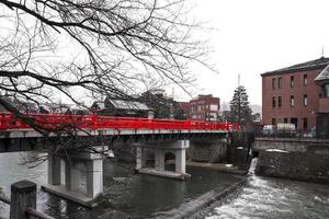 Red bridge in little Kyoto in a little snowing and raining fall. photo