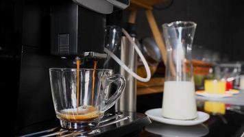la cafetera recién hecha está vertiendo agua de café en un vaso transparente. Las bebidas en los restaurantes son populares para beber en general. taza de café americano con espuma de crema. video