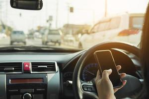 primer plano de un hombre conduciendo un coche peligrosamente mientras usa el teléfono móvil foto