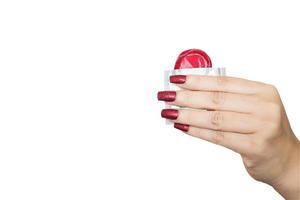 Lady's hand showing red condom and package with white copy space background. Photo includes CLIPPING PATH.