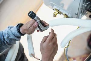 Man is installing wall compressor of air conditioner during hot season photo