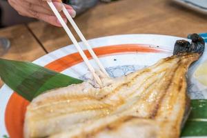 pescado cocido japonés en un plato sobre una mesa de madera en un restaurante japonés abierto las 24 horas. foto