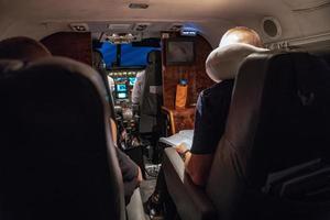 un hombre leyó un libro en el pequeño avión privado en la noche bajo la luz. foto